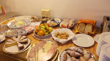 Ein reichhaltiges Buffet mit verschiedenen Speisen, darunter Gebäck, Obst und Sandwiches.