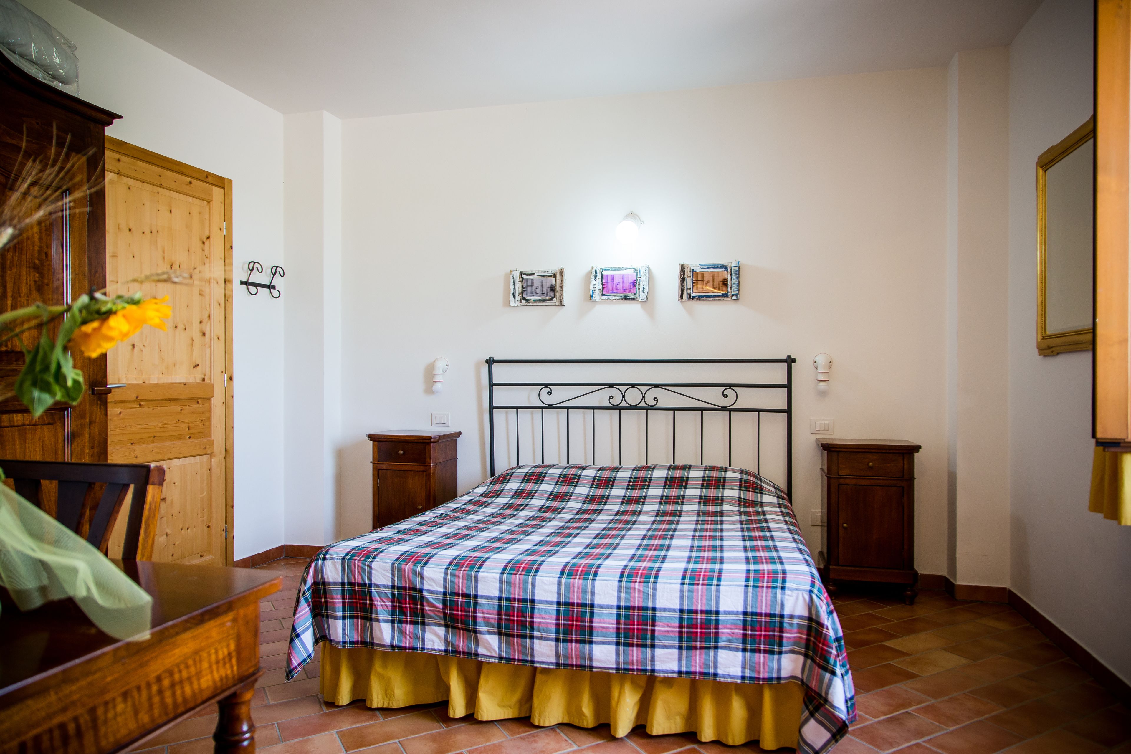 A bedroom with a bed, wooden furniture, and a wall-mounted light fixture.