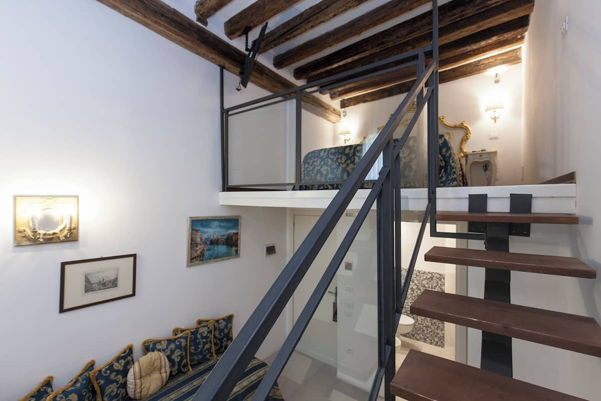 A staircase with a glass railing leading to a second-floor bedroom.