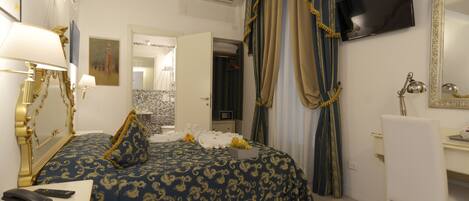 Une chambre d’hôtel comprenant un lit, une table de chevet, une lampe, une télévision, un bureau, une chaise et un miroir.