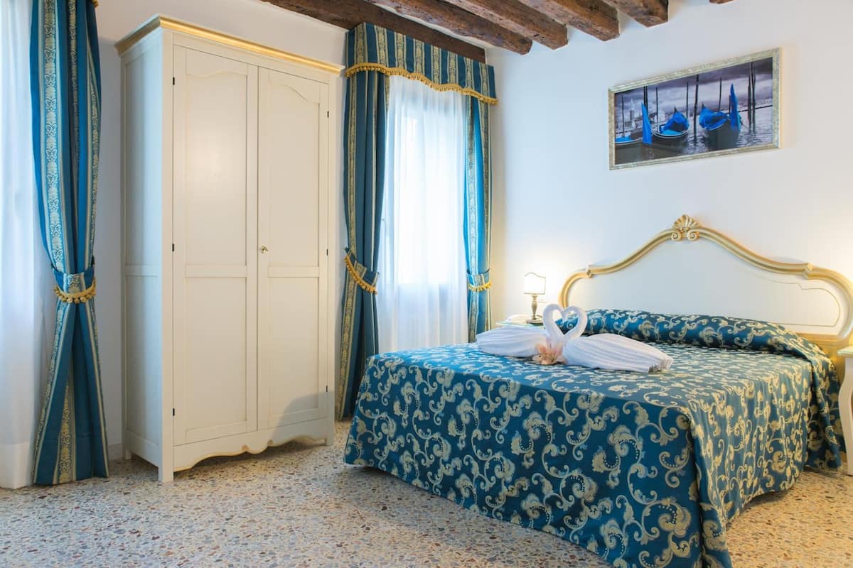 A bedroom with a bed, a wardrobe, and a painting on the wall.