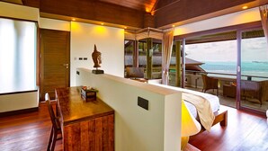 Une chambre d’hôtel moderne avec un plafond en bois, un coin repas, un lit et un balcon offrant une vue sur l’océan.