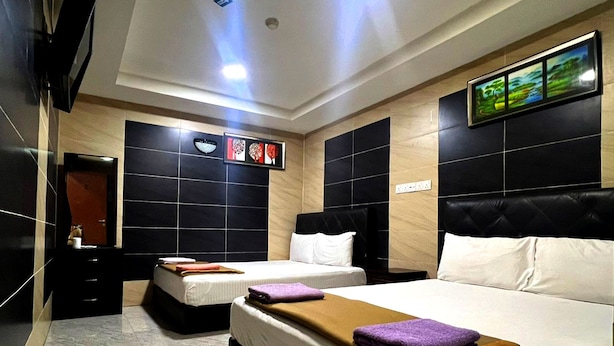 Une chambre d’hôtel avec deux lits, un grand miroir, un téléviseur fixé au mur et un tableau encadré.