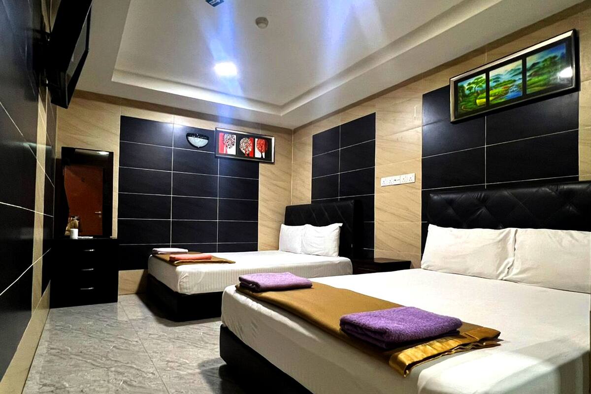 Habitación de hotel con dos camas, un espejo grande, un televisor de pared y un cuadro enmarcado.