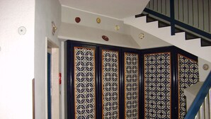 Uma escadaria com corrimão azul e parede estampada com painéis decorativos.