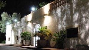 Un bâtiment doté d’une entrée fermée par un portail, de plantes en pot et d’une façade en pierre.