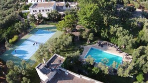 Un vaste domaine doté de plusieurs courts de tennis, d’une piscine et d’un grand patio entouré d’une végétation luxuriante.