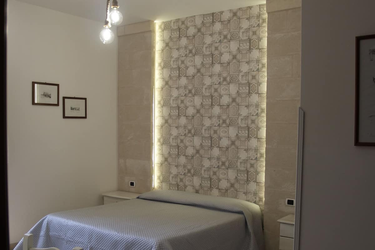 Une chambre à coucher avec un lit, un bureau et une chaise. Deux tableaux encadrés sont accrochés au mur.