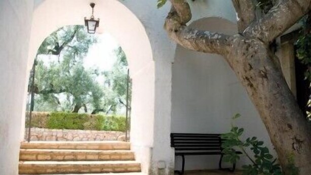 Un escalier en pierre mène à un espace extérieur aménagé avec un banc et un lampadaire.