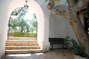 A stone staircase leading to an outdoor area with a bench and a lamp post. - Masseria Don Sante (Fasano)