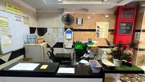 A reception desk with a computer, a fan, and a clock on the wall. There are signs on the wall and a red machine on the right. - Shah Alam Business Hotel (Shah Alam)