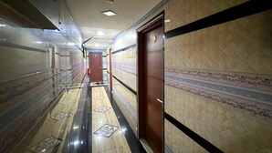 A corridor with patterned walls and a polished floor, leading to a door with a number plate. - Shah Alam Business Hotel (Shah Alam)