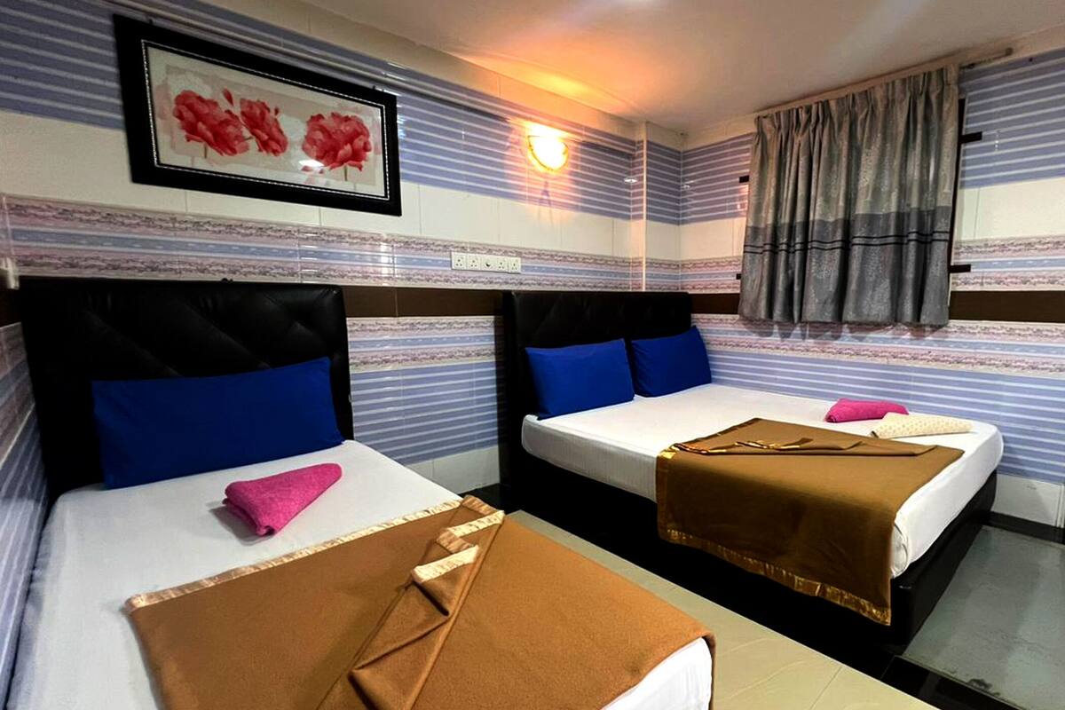 Habitació d'hotel amb dos llits, cadascun amb un capçal, almoinos i llençols. Hi ha un quadre encimbellat a la paret sobre els llits, una finestra amb cortines i una làmpada de paret.