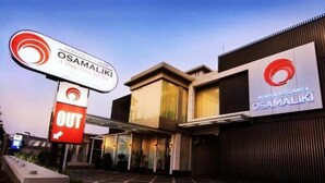 Un edificio moderno con un letrero que dice "OSAMALIKI" y una flecha señalando hacia la izquierda.