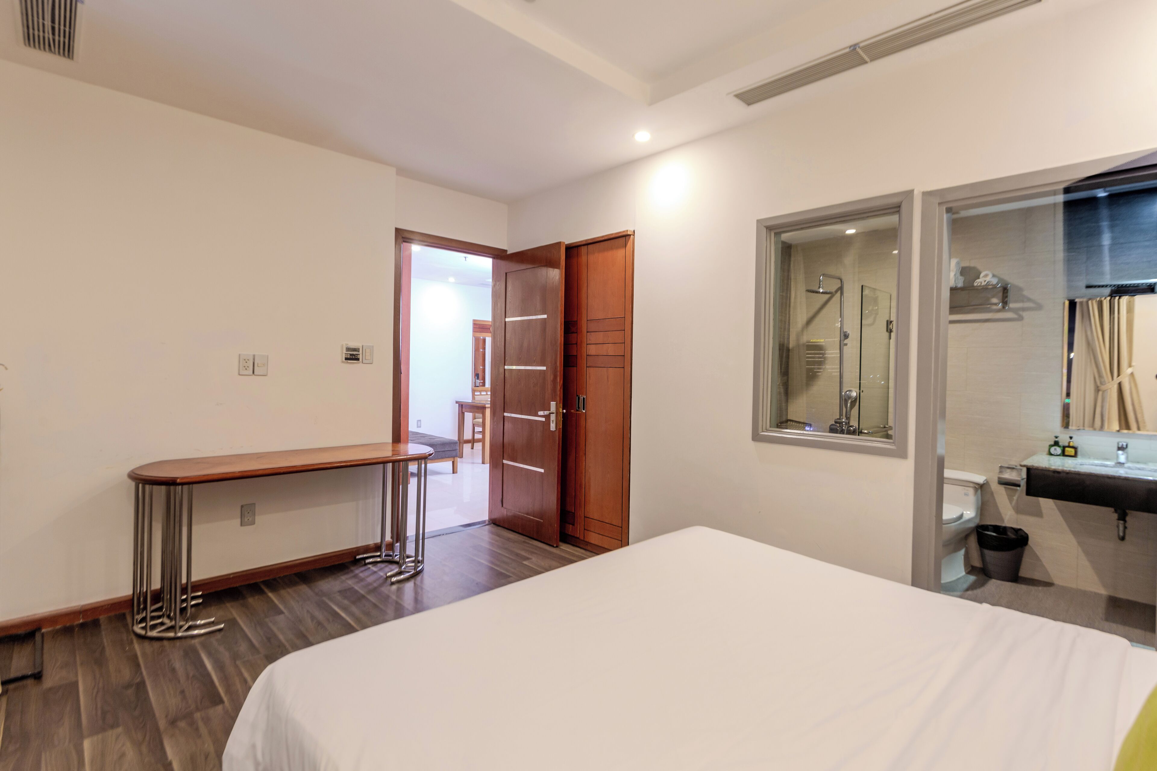 Habitació d'hotel amb llit, taula petita, zona de dutxa i bany amb rentatge i vàter.