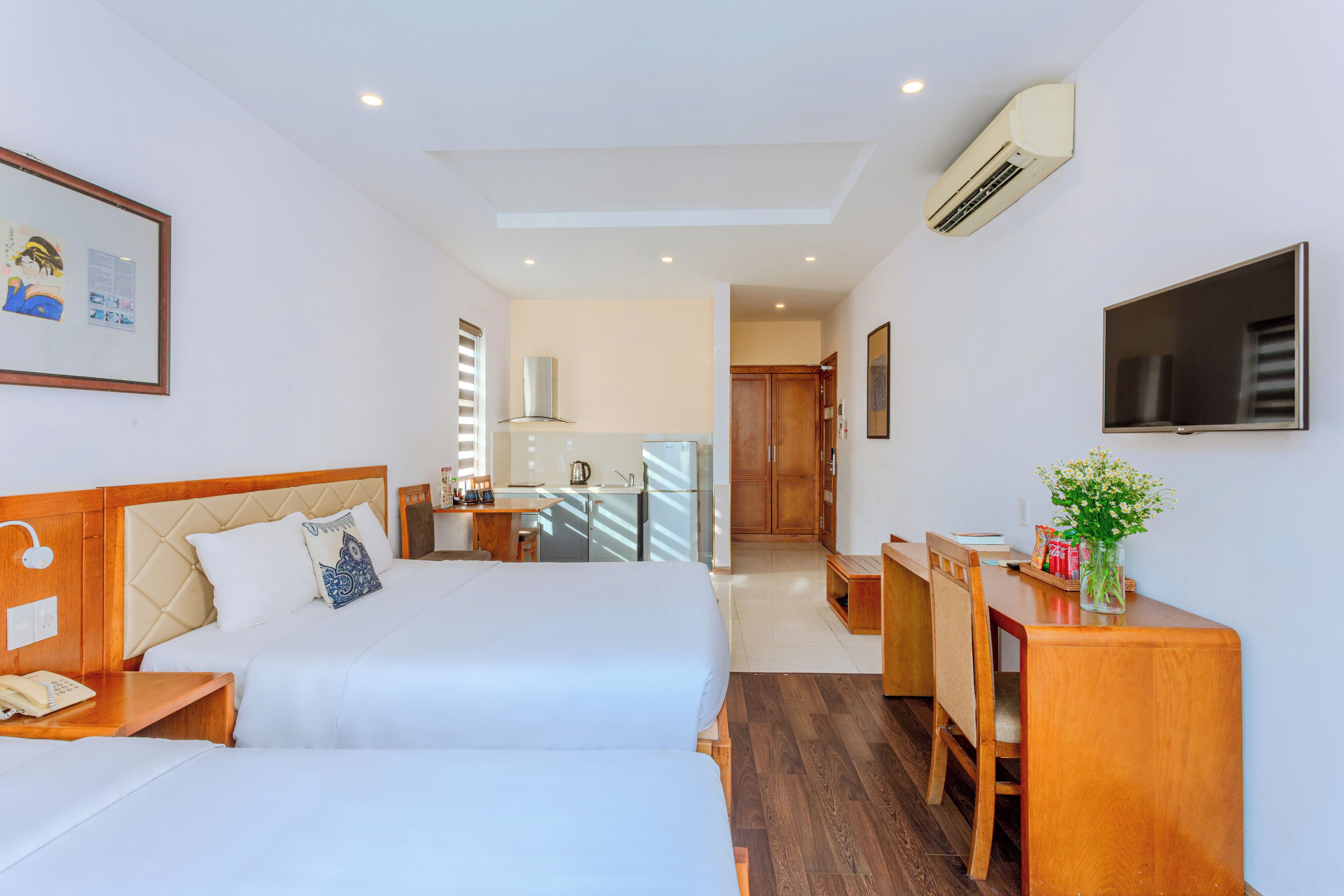 Una habitación de hotel con dos camas, un escritorio, un televisor y una kitchenette.