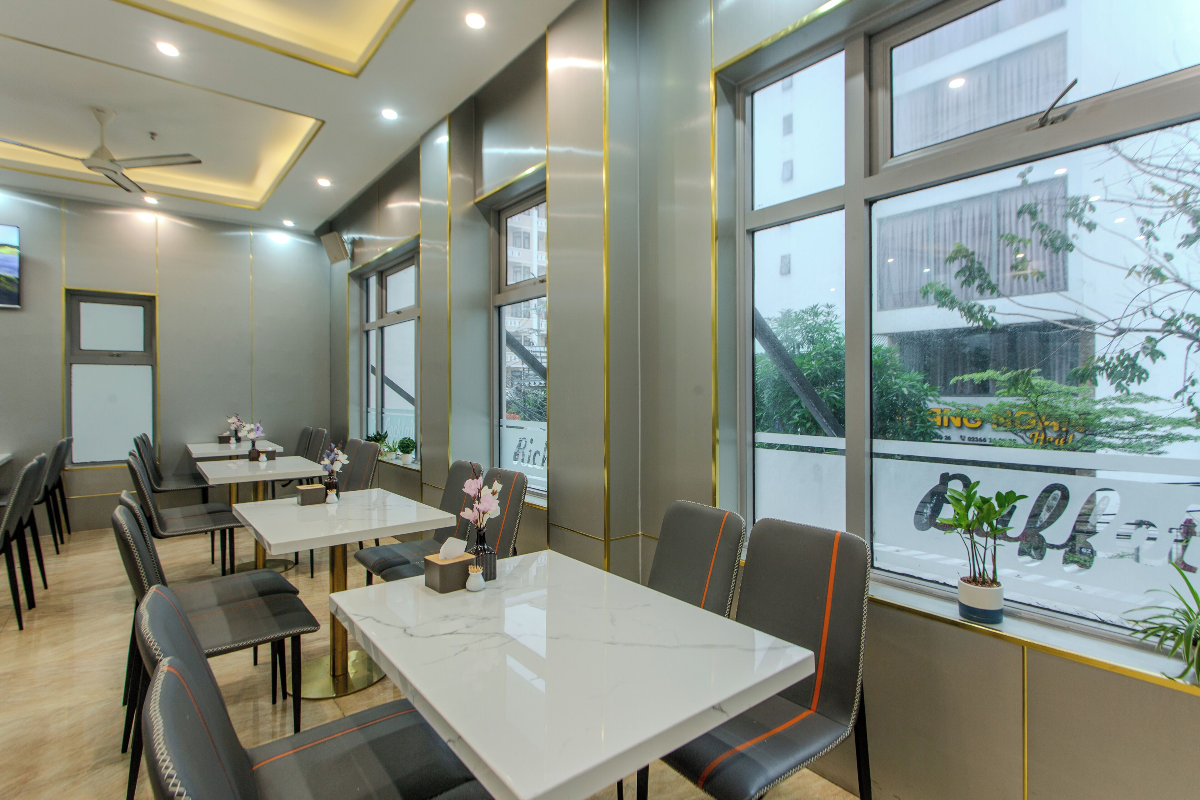 A modern dining area with tables and chairs, large windows, and a view of the outside.