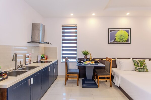 Una habitación de hotel compacta con kitchenette, zona de comedor y cama.