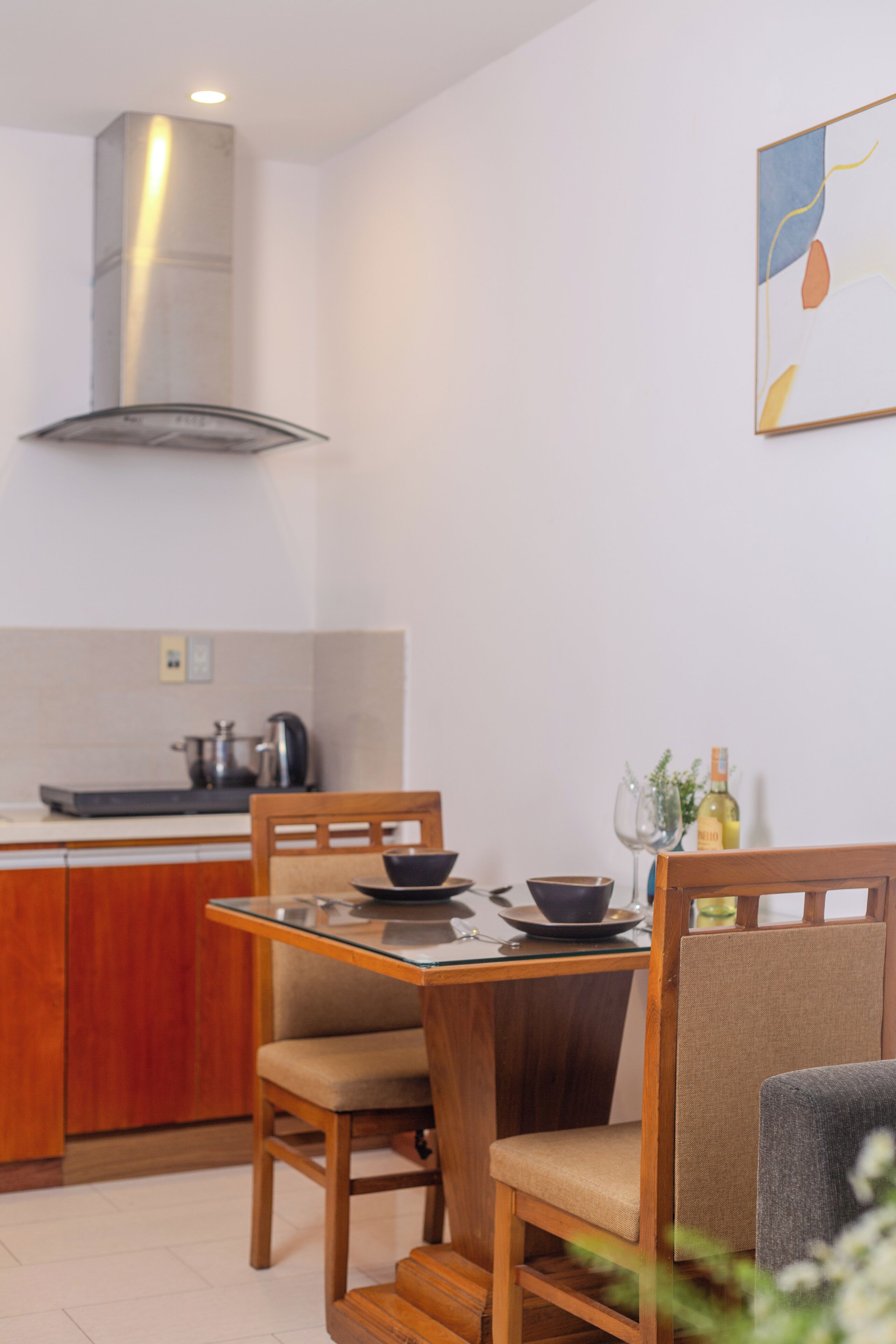 A modern kitchen with a dining area, wooden furniture, and a stainless steel range hood.