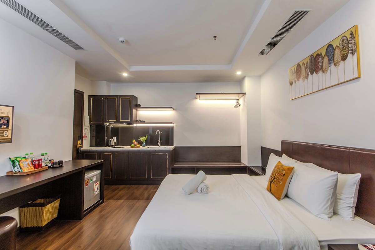 Habitación de hotel con cama, escritorio, kitchenette y baño.
