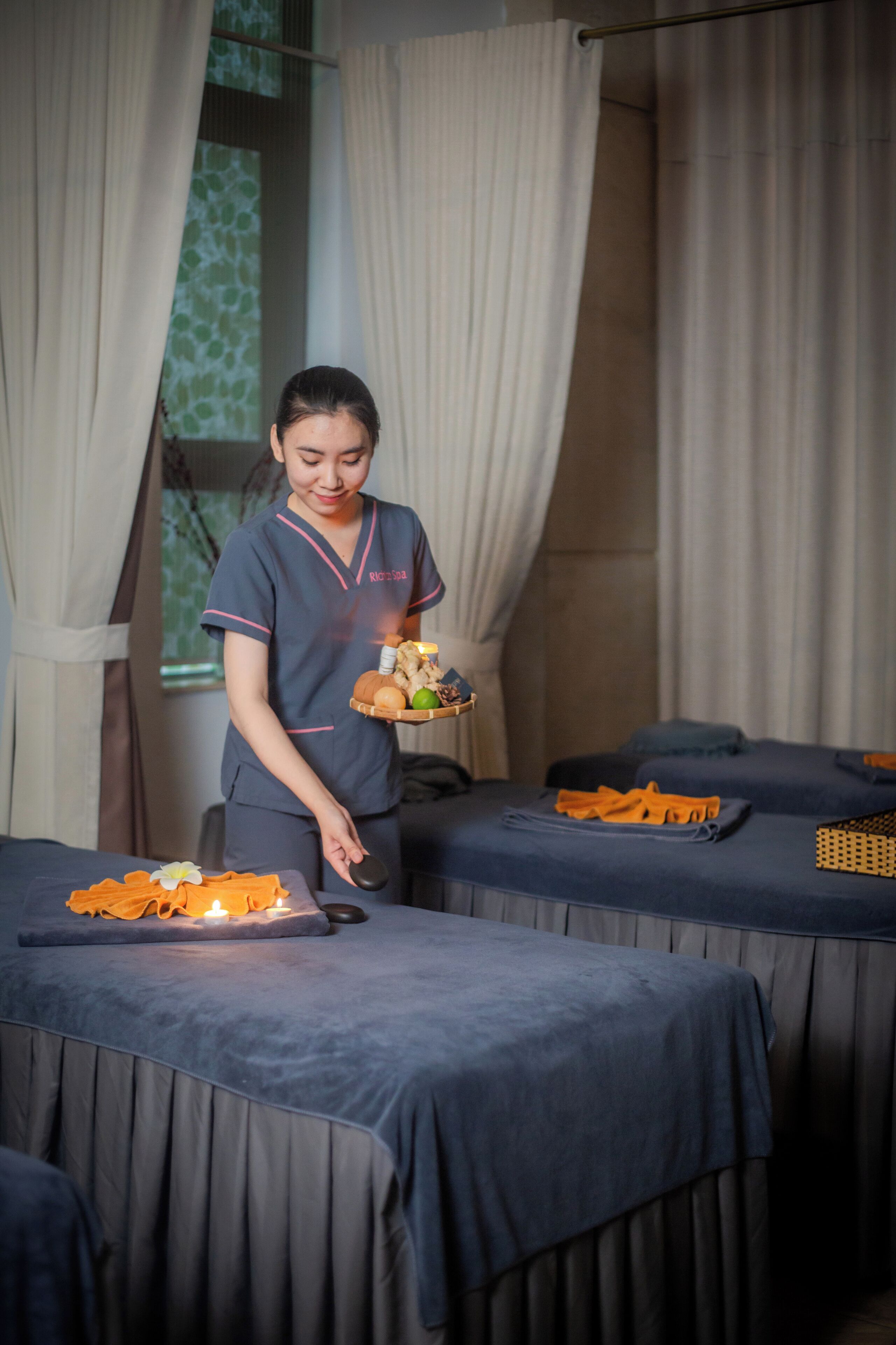 A spa room with two massage tables, a tray with candles, and a tray with spa products.
