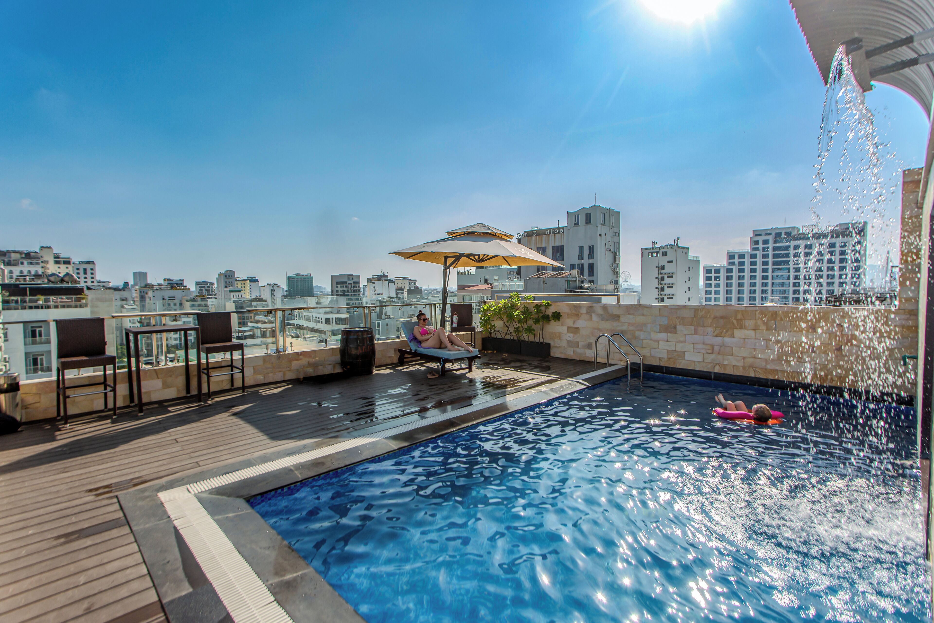 Una piscina al aire libre, sombrillas, sillones reclinables de piscina