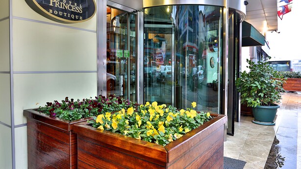 A hotel entrance with a sign reading "Hotel Princess Boutique," a revolving door, and a planter box with yellow flowers. - Hotel Princess Boutique (Istanbul)