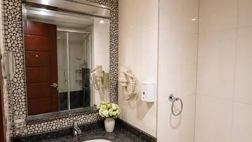 A bathroom with a marble sink, a mirror, a toilet, and a trash bin.