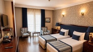 A hotel room with a large bed, two bedside tables, a desk with a chair, a television, and a window with curtains. - Hotel Princess Boutique (Istanbul)