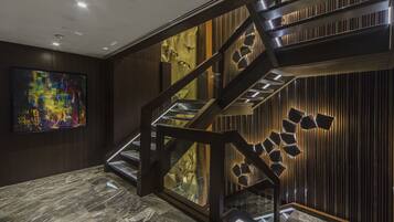 A modern staircase with glass railings and a geometric light fixture.