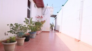 A corridor with potted plants and a tiled floor. - Just Guest House (Chennai)