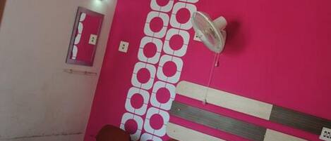 Habitación de hotel con cama, escritorio, silla, espejo y lámpara en el techo.