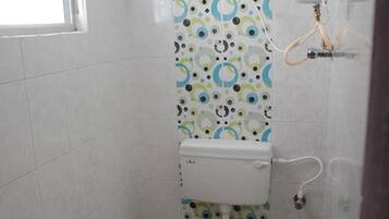 Un baño pequeño con inodoro, ducha y soporte para papel higiénico.