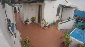 A courtyard with potted plants, a white building, and an air conditioning unit. - Just Guest House (Chennai)