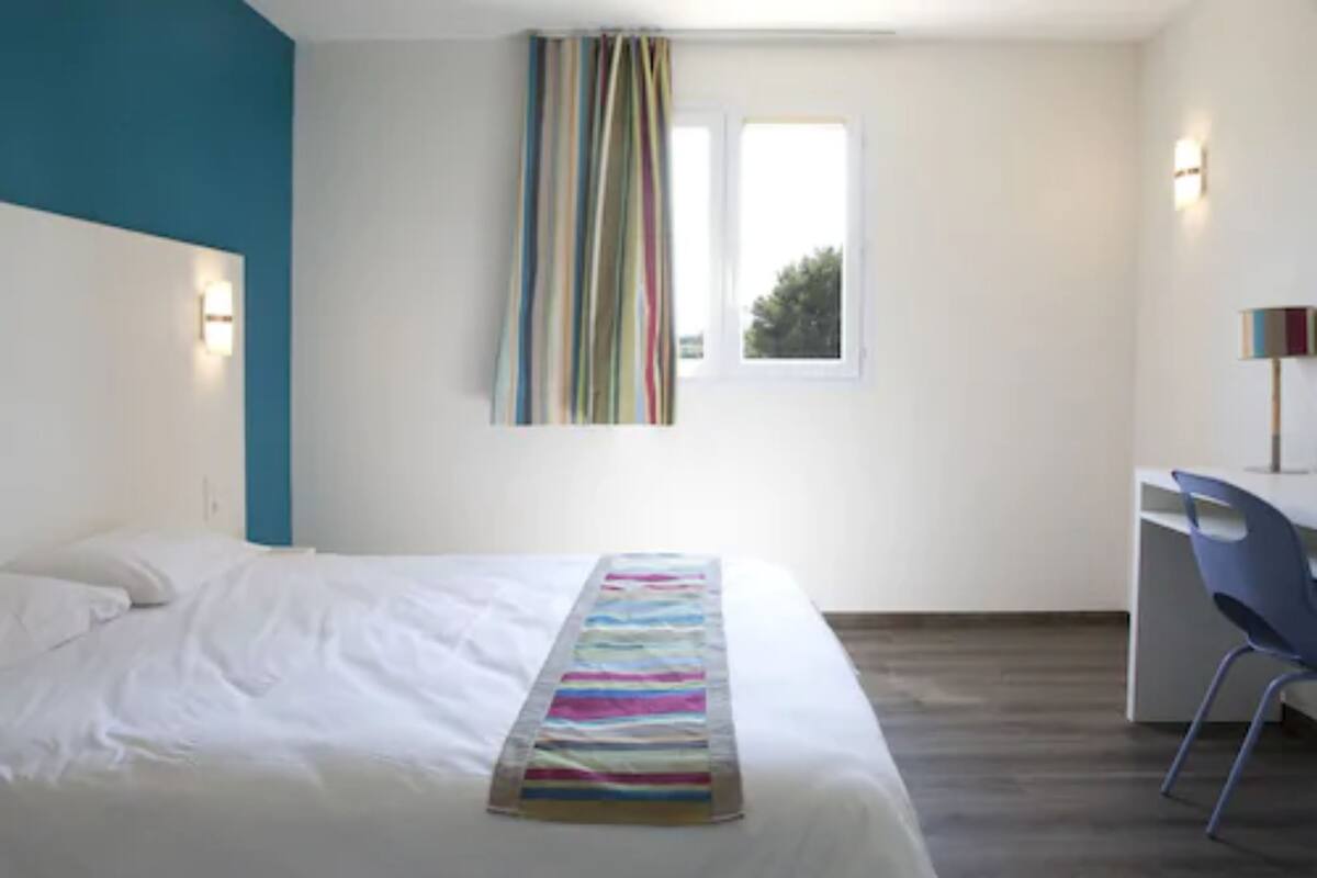 A bedroom with a bed, a desk, and a chair.