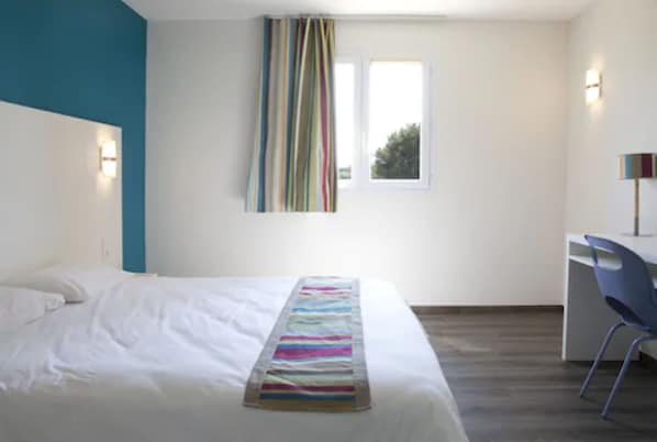 Un dormitorio con cama, escritorio y silla.