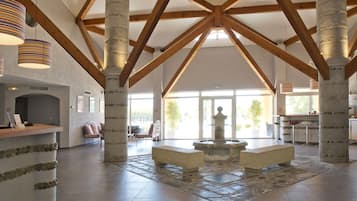 A spacious lobby with high ceilings, stone pillars, and a central seating area.