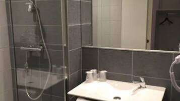 A modern bathroom with a glass-enclosed shower, a white sink, and a towel rack.
