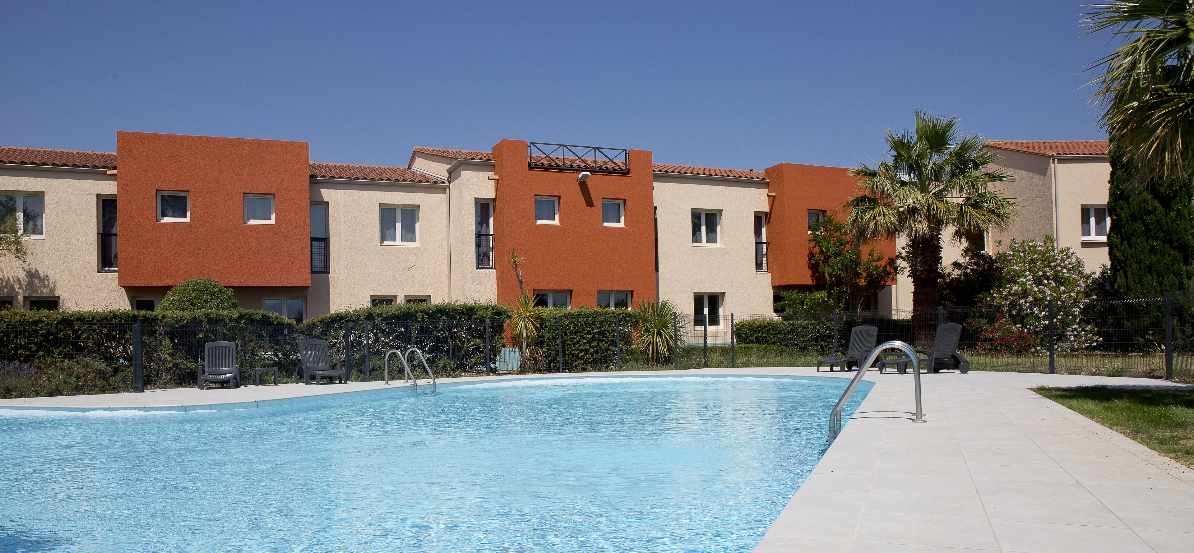 A swimming pool with lounge chairs and a clear sky.
