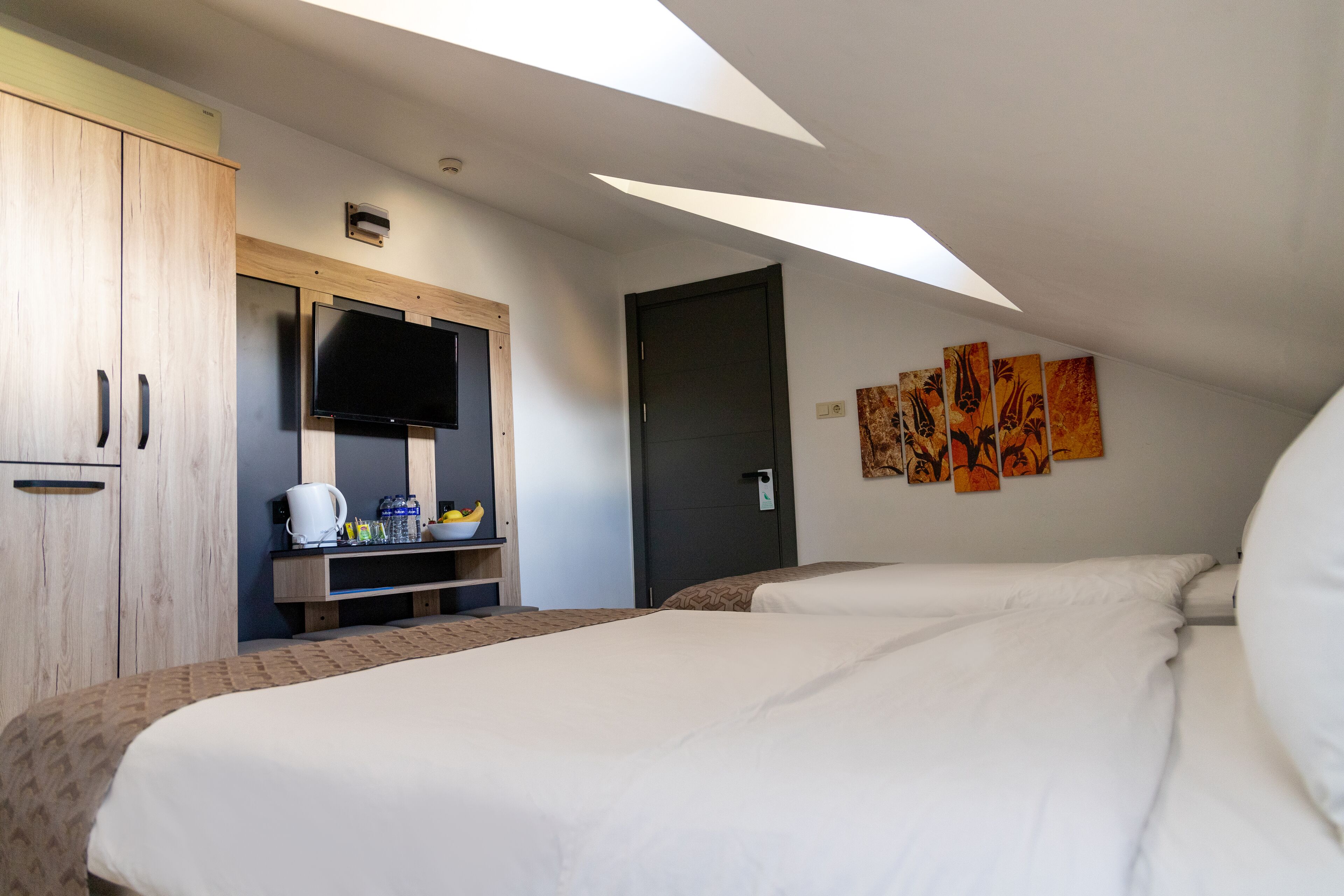Habitación de hotel con cama, televisión, cafetera y obras de arte en la pared.