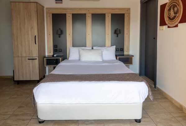 Un dormitorio con una cama grande, cabecera de madera, mesitas de noche y un armario.