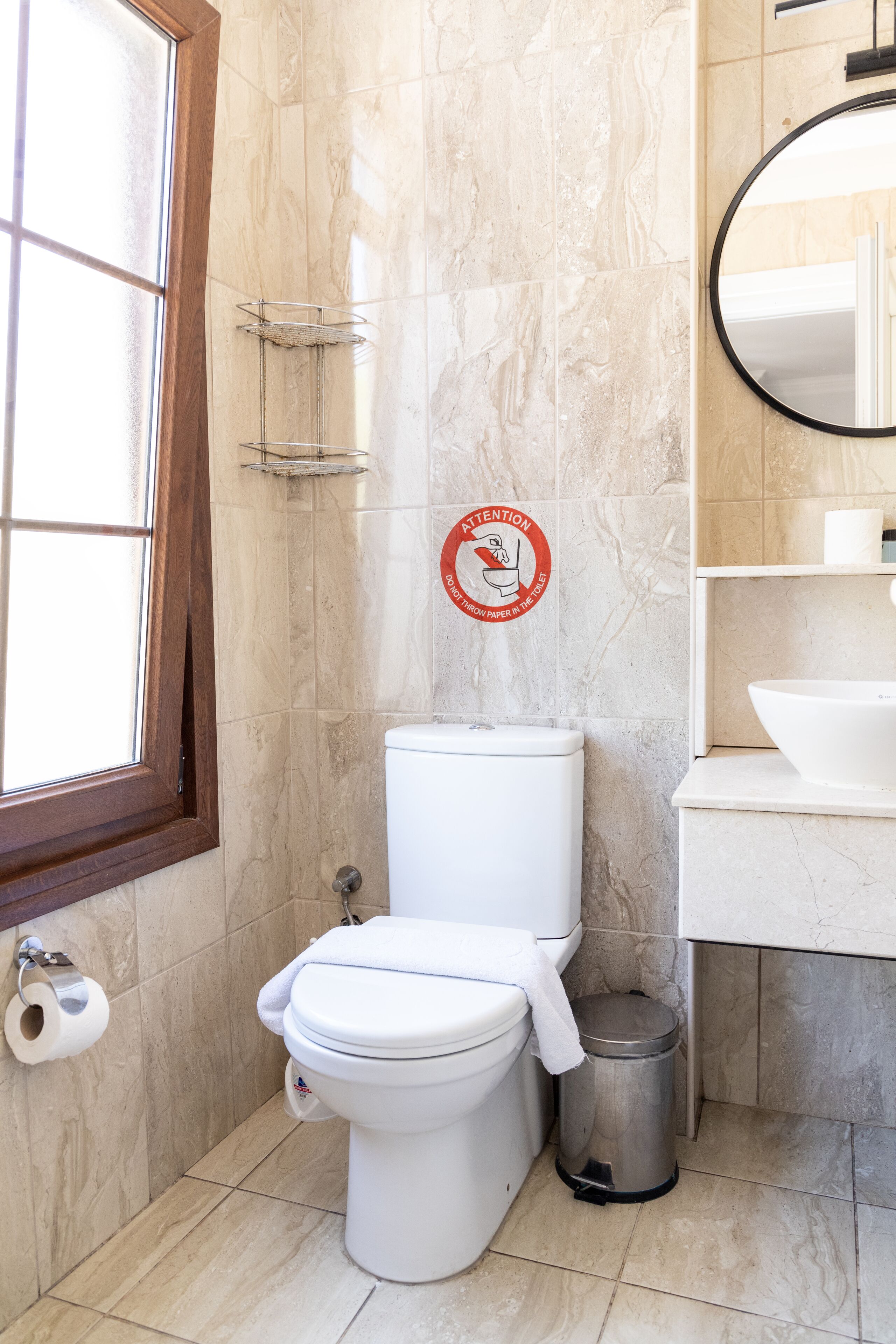 Ein Badezimmer mit Toilette, Mülleimer, Handtuchhalter und Spiegel.