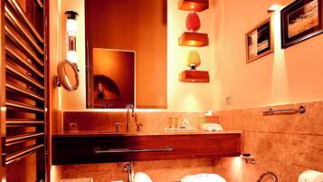 A modern bathroom with a wooden ceiling, a large mirror, a sink, and a toilet.