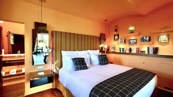 Une chambre d’hôtel avec un grand lit, un miroir, une table de chevet et un petit bureau avec une lampe.