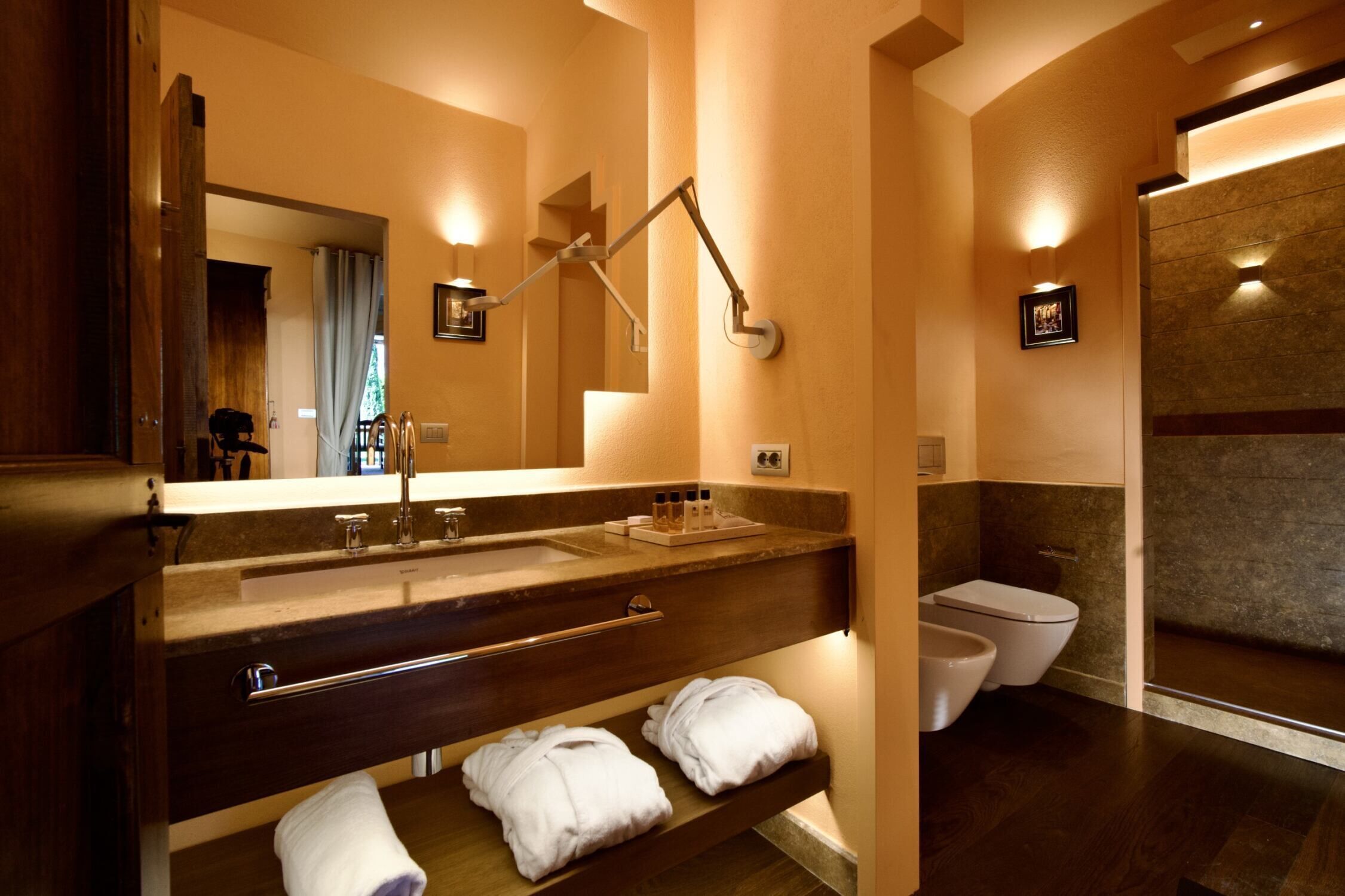 Een moderne badkamer met een grote spiegel, een wastafel met handdoekhouder, een toilet en een douchehoek.