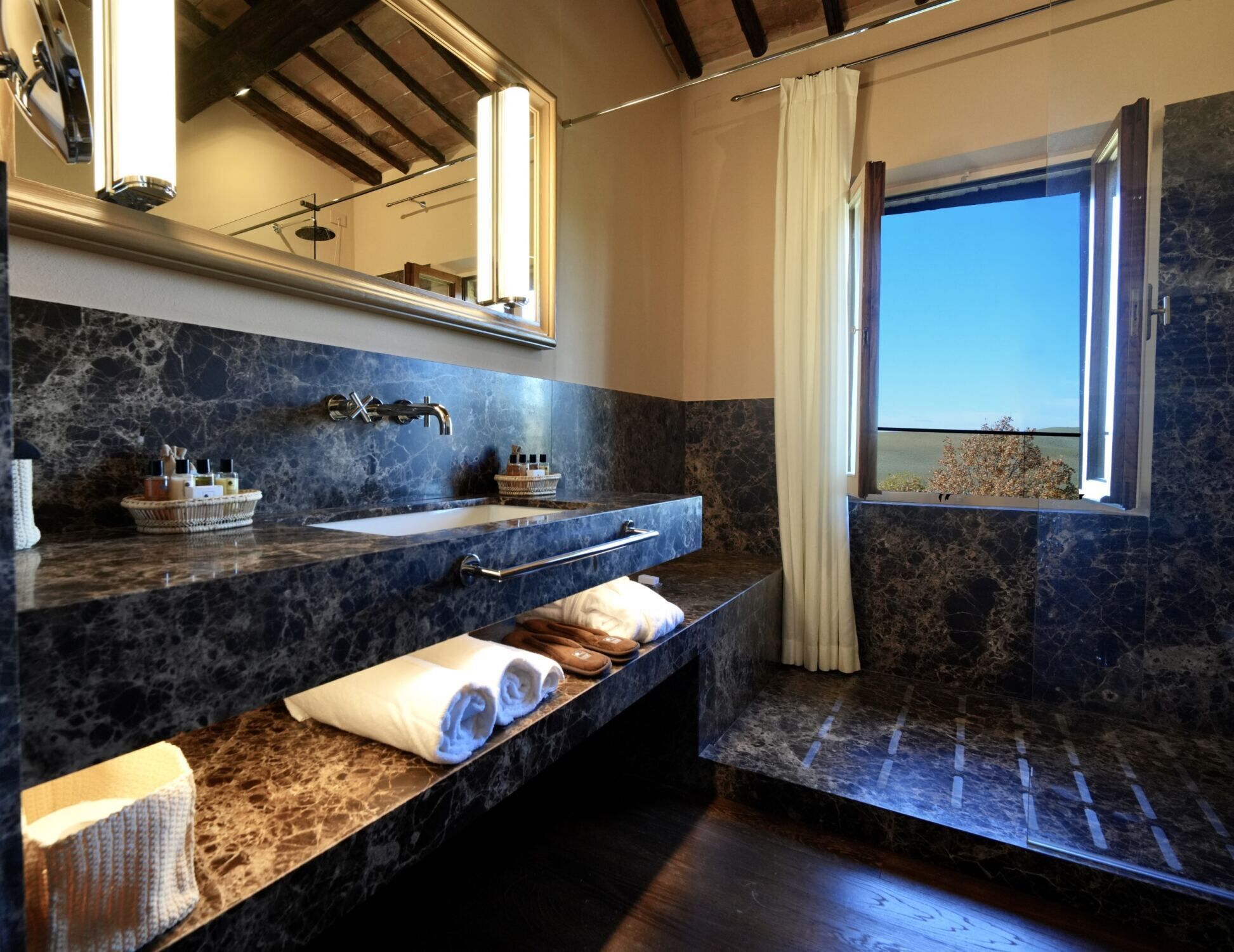 A modern bathroom with a large sink, a mirror, and a window with a view.