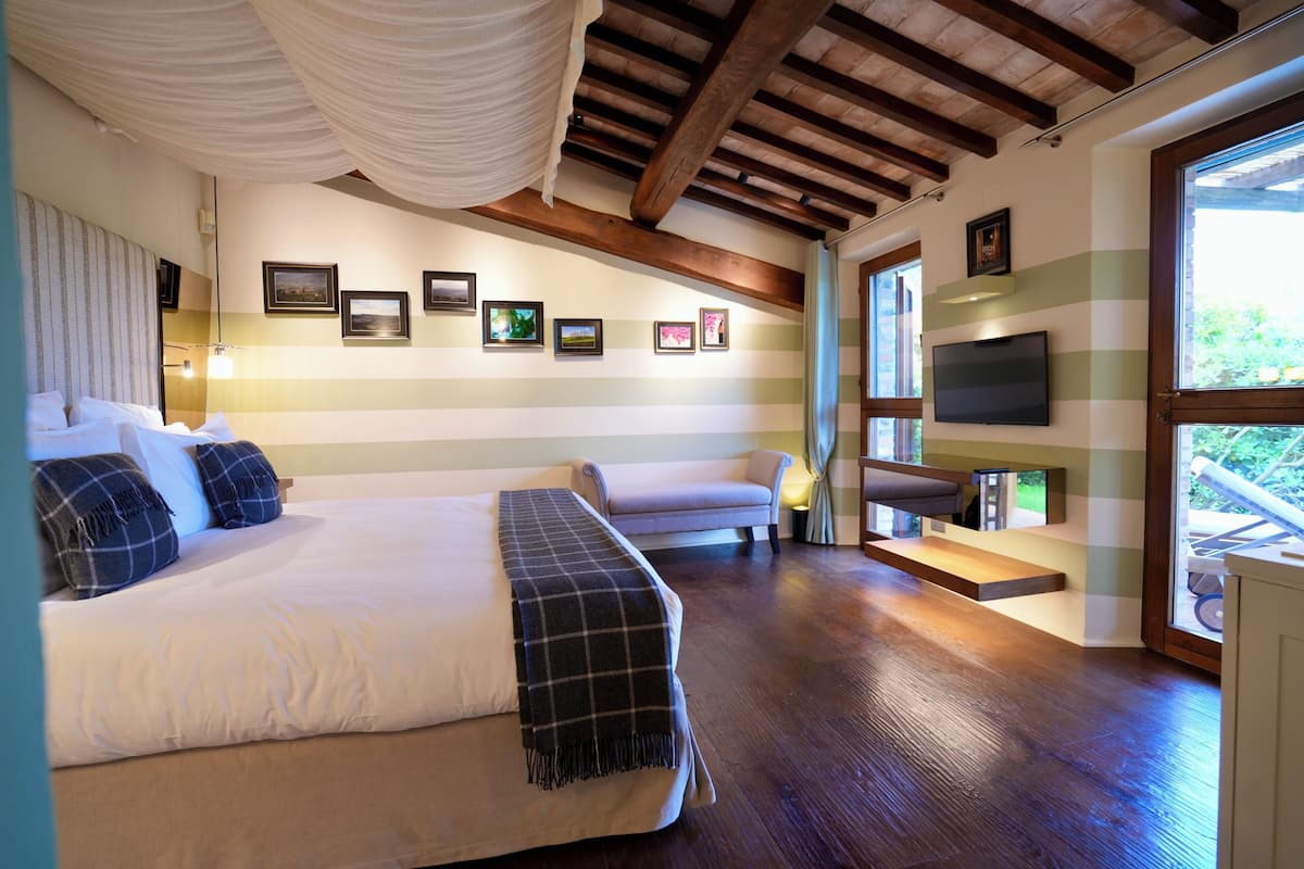 A hotel room with a large bed, a sofa, a TV, and framed pictures on the wall.