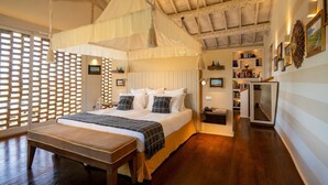 Un dormitorio con cama con dosel, suelo de madera, una mesita de noche y una estantería empotrada.