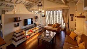 Una sala de estar acogedora con sofá, mesa de centro, televisión, estanterías y una lámpara decorativa.