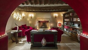 Una sala de lectura acogedora con chimenea, estanterías y asientos cómodos.